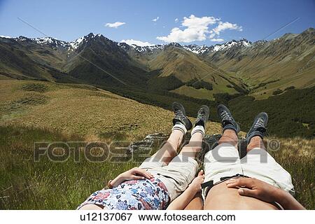 Man and woman laying in grass by mountains low section View Large Photo Image Stock Photo - Man and woman laying in grass by mountains low section. Fotosearch