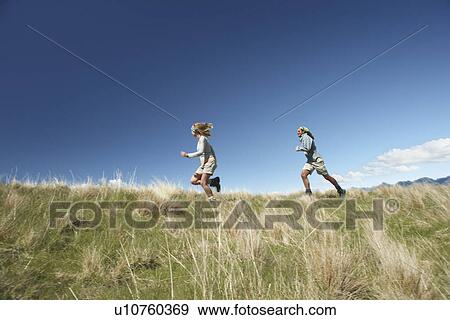 Man and woman running through field View Large Photo Image Stock Photo - Man and woman running through field. Fotosearch