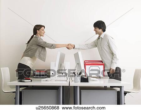 Man and Woman Shaking Hands over Desks side view View Large Photo Image Stock Photo - Man and Woman Shaking Hands over Desks side view. Fotosearch