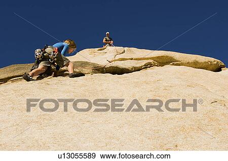 Man assisting woman climbing cliff low angle view View Large Photo Image Stock Photo - Man assisting woman climbing cliff low angle view. Fotosearch