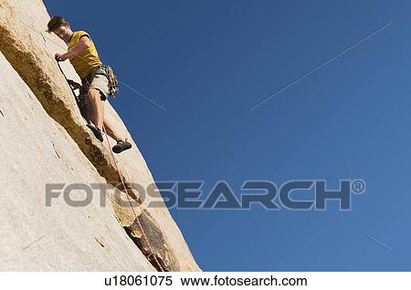 Stock Photography - Man Climbing on Cliff. Fotosearch