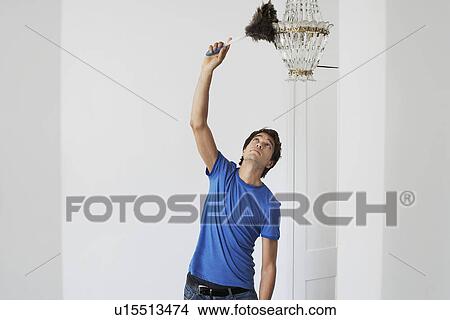 Man dusting crystal chandelier in home View Large Photo Image Picture - Man dusting crystal chandelier in home. Fotosearch