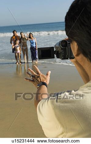 Man filming family on beach View Large Photo Image Picture - Man filming family on beach. Fotosearch