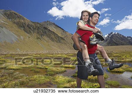 Man giving woman piggy-back ride through pond near mountains View Large Photo Image Stock Photography - Man giving woman piggy-back ride through pond near mountains. Fotosearch