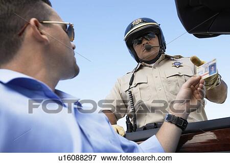 Man handing licence to police officer low angle view View Large Photo Image Stock Photo - Man handing licence to police officer low angle view. Fotosearch
