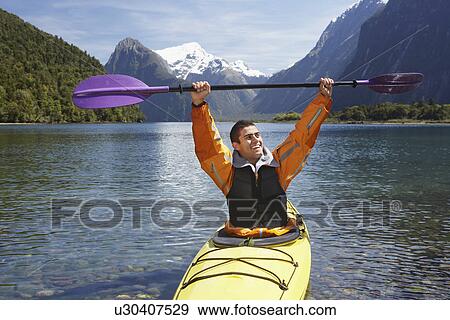 Man hoisting oar of kayak over head in mountain lake View Large Photo Image Stock Photo - Man hoisting oar of kayak over head in mountain lake. Fotosearch