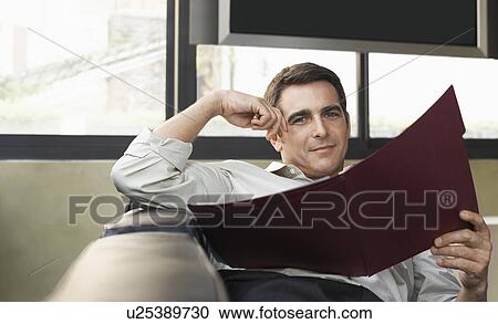 Man holding folder sitting on sofa half length View Large Photo Image Stock Image - Man holding folder sitting on sofa half length. Fotosearch