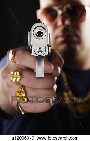 Stock Photo - Man holding gun focus on hand. Fotosearch