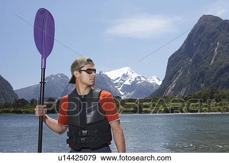 Man holding oar on shore of mountain lake View Large Photo Image Stock Photo - Man holding oar on shore of mountain lake. Fotosearch