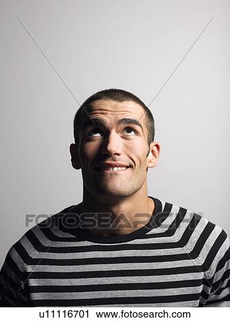 Stock Image - Man in striped shirt in studio looking up head and shoulders. Fotosearch