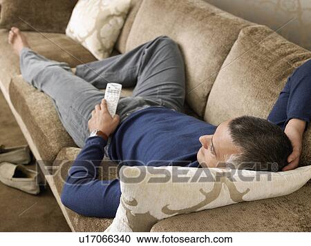 Man laying on sofa watching TV View Large Photo Image Stock Image - Man laying on sofa watching TV. Fotosearch