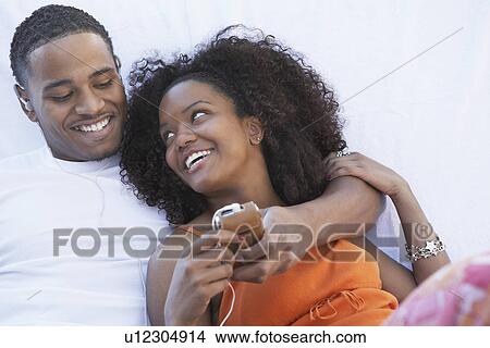 Man listening to mp3 player hugging girlfriend View Large Photo Image Picture - Man listening to mp3 player hugging girlfriend. Fotosearch