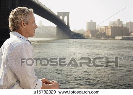 Man looking at river by Brooklyn Bridge View Large Photo Image Stock Photo - Man looking at river by Brooklyn Bridge. Fotosearch