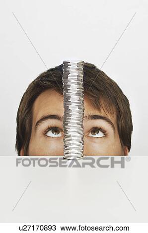 Stock Image - Man looking at stack of coins. Fotosearch
