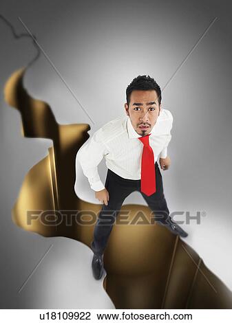 Stock Image - Man looking up over crack in ground full length digital composite. Fotosearch