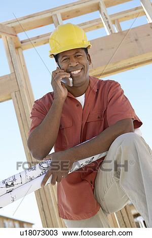 Man on building site on cell phone View Large Photo Image Stock Image - Man on building site on cell phone. Fotosearch