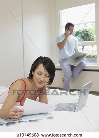 Man on cell phone by window woman reading on bed View Large Photo Image Stock Photo - Man on cell phone by window woman reading on bed. Fotosearch
