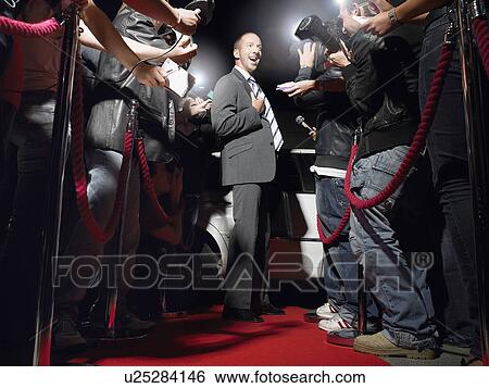Stock Photograph - Man on red carpet in front of paparazzi. Fotosearch