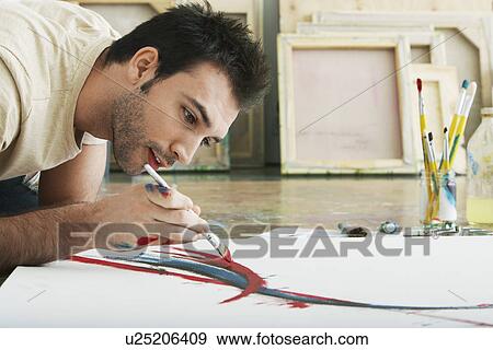 Man painting on canvas on studio floor View Large Photo Image Stock Photo - Man painting on canvas on studio floor. Fotosearch