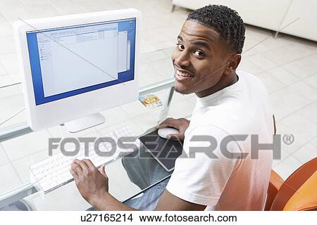 Picture - Man sitting at computer (elevated view). Fotosearch