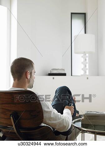Picture - Man Sitting in Chair Listening to MP3 Player back view. Fotosearch