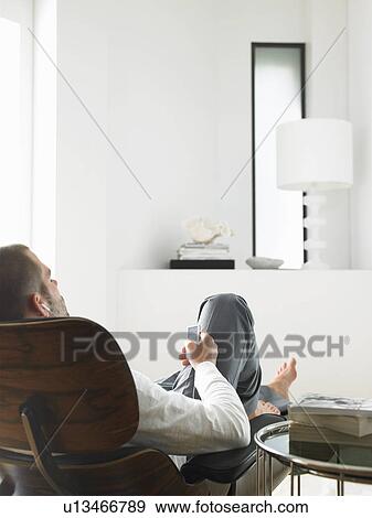 Stock Photo - Man Sitting in Chair Listening to MP3 Player back view. Fotosearch