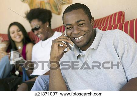 Stock Photo - Man sitting on sofa talking on cell phone portrait. Fotosearch