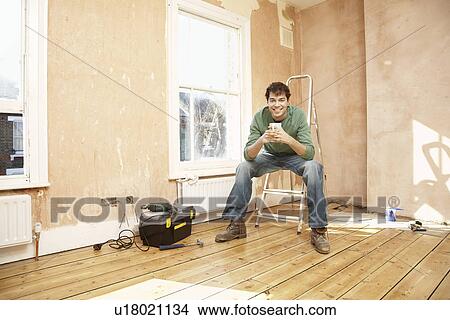 Picture - Man sitting on step ladder in unrenovated room. Fotosearch