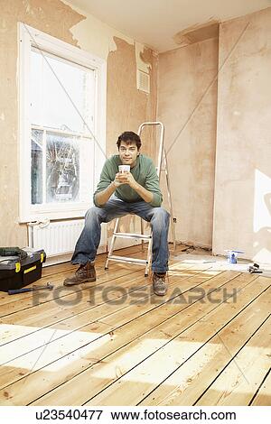 Man sitting on step ladder in unrenovated room View Large Photo Image Stock Photo - Man sitting on step ladder in unrenovated room. Fotosearch