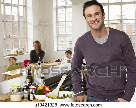 Stock Photo - Man standing in kitchen smiling (portrait). Fotosearch