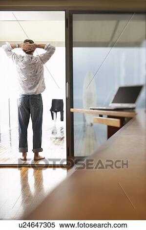 Stock Photography - Man standing on balcony relaxing back view.. Fotosearch