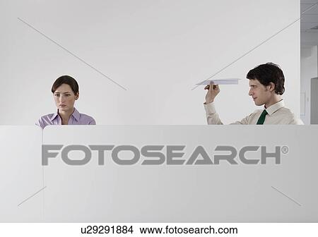 Man throwing paper aeroplane at female colleague in office View Large Photo Image Picture - Man throwing paper aeroplane at female colleague in office. Fotosearch