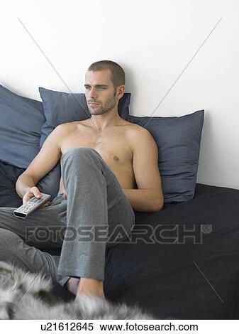 Man watching TV on sofa View Large Photo Image Stock Photography - Man watching TV on sofa. Fotosearch