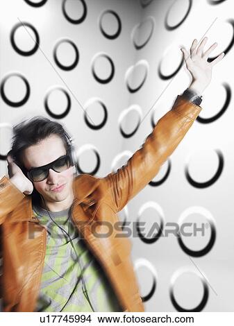 Man wearing headphones and sunglasses blurred motion in front of spotty wall View Large Photo Image Picture - Man wearing headphones and sunglasses blurred motion in front of spotty wall. Fotosearch