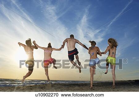 Man with four women running and jumping on beach back view View Large Photo Image Stock Image - Man with four women running and jumping on beach back view. Fotosearch