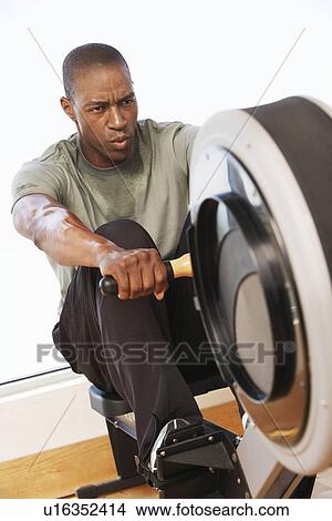 Picture - Man working out on Rowing Machine in health club. Fotosearch