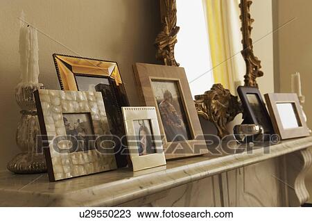 Stock Image - Marble Fireplace Mantel With Framed Pictures and mirror. Fotosearch