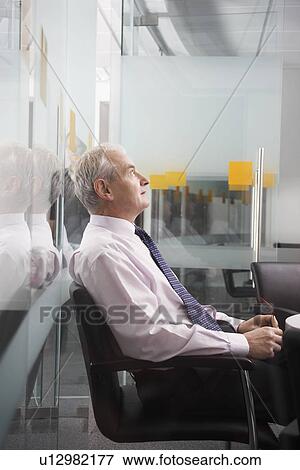 Stock Photo - Mature businessman sitting in conference room side view. Fotosearch