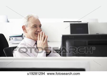Mature businessman sitting with folded hands in office cubicle View Large Photo Image Picture - Mature businessman sitting with folded hands in office cubicle. Fotosearch