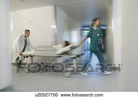 Stock Image - Medical Workers Moving Patient on gurney through hospital corridor motion blur. Fotosearch