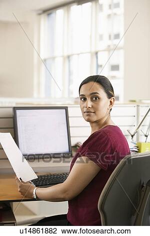Mid-adult female office worker at cubicle holding paperwork portrait View Large Photo Image Stock Image - Mid-adult female office worker at cubicle holding paperwork portrait. Fotosearch