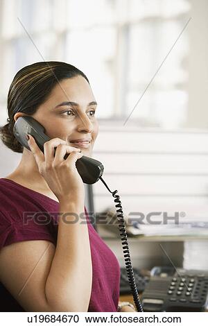 Mid-adult female office worker in cubicle on phone View Large Photo Image Stock Image - Mid-adult female office worker in cubicle on phone. Fotosearch