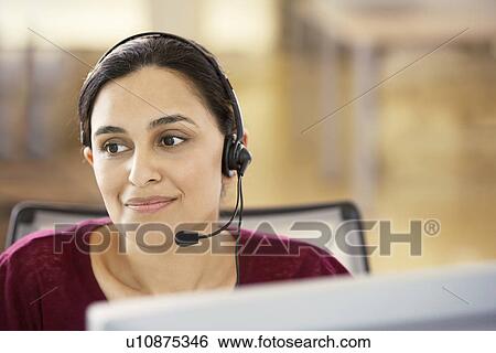 Mid-adult female office worker sitting in cubicle wearing headset portrait View Large Photo Image Stock Photograph - Mid-adult female office worker sitting in cubicle wearing headset portrait. Fotosearch