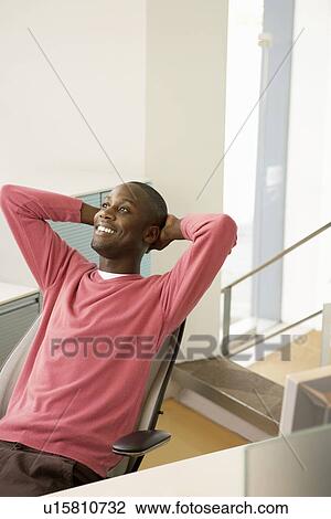 Mid-adult male office worker reclining at desk relaxing View Large Photo Image Stock Image - Mid-adult male office worker reclining at desk relaxing. Fotosearch