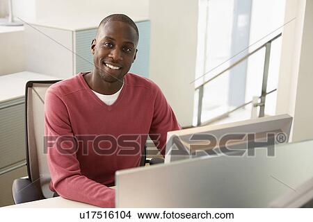 Picture - Mid-adult male office worker working at desk portrait. Fotosearch