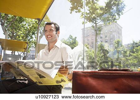 Mid-adult man reading newspaper at bus stop View Large Photo Image Stock Image - Mid-adult man reading newspaper at bus stop. Fotosearch