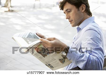 Mid-adult man reading newspaper on street View Large Photo Image Stock Photo - Mid-adult man reading newspaper on street. Fotosearch