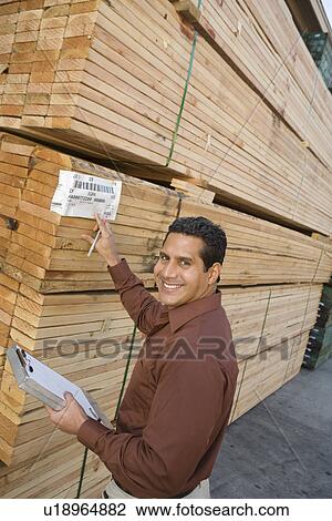 Stock Image - Mid-adult man stock-taking in warehouse. Fotosearch