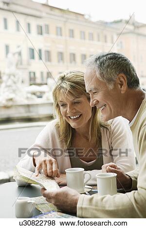 Stock Photo - Middle-aged couple at outdoor cafe in Rome looking at map head and shoulders. Fotosearch