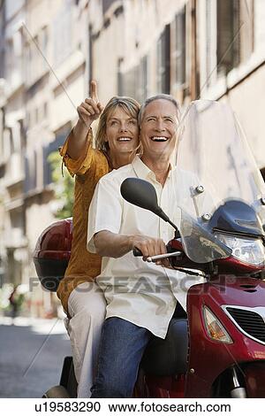 Stock Image - Middle-aged couple sightseeing on scooter in Rome Italy. Fotosearch